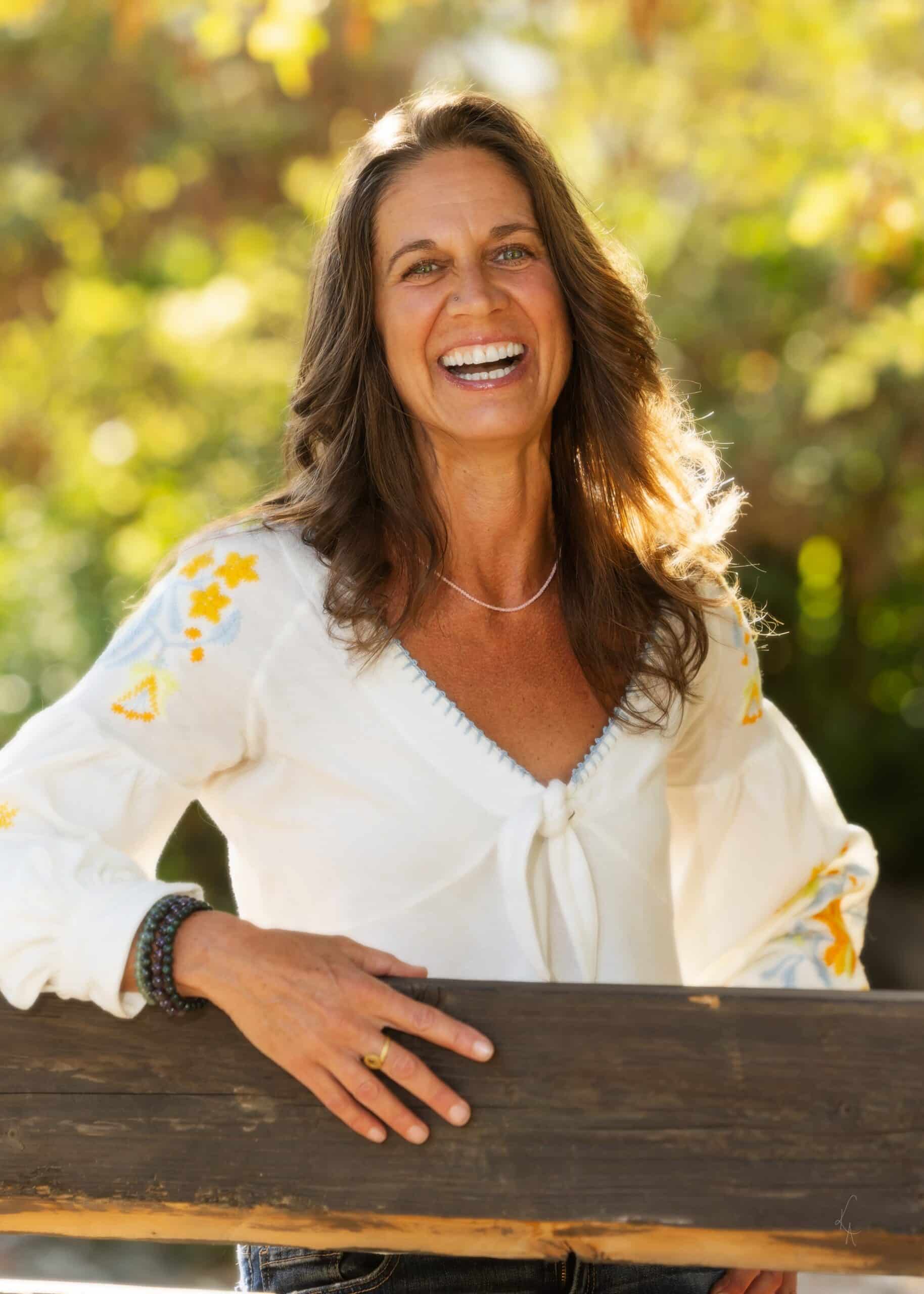 Jennifer Jo Kenworthy laughing candidly, leaning against a railing out in nature